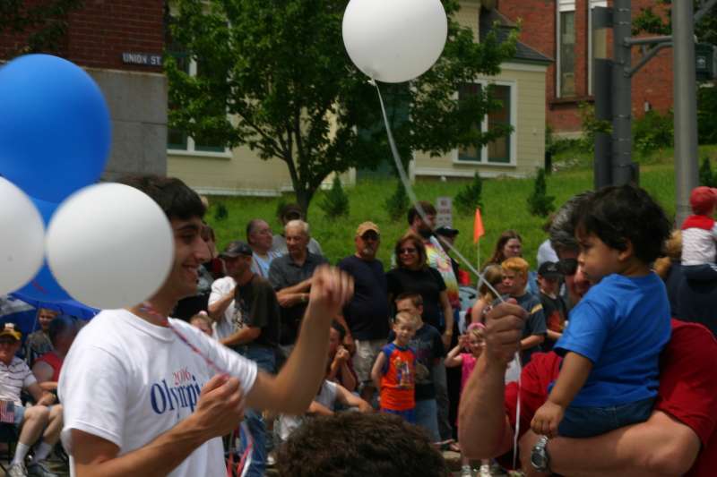 A worker for the Olympia Snowe campaign hands a balloon to a boy along the Fourth of July parade route in Bangor, Maine.