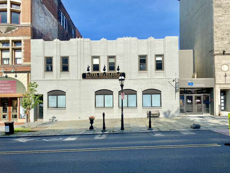 Built in the early 20th Century, this Art Deco-style building features a painted brick exterior, pilasters that stair-step in and out of the facade with vertical lines of single bricks in the middle of each pilaster except at the ends, recessed