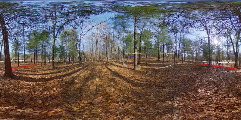 A wooded and hilly landscape. Trees are bare. Ahead on a low hill are four blue rectangles with the words "Lexington militia" above them. Pan to the right you will see words "Rocky Outcrop. Pan to the right you will see two red rectangles and the
