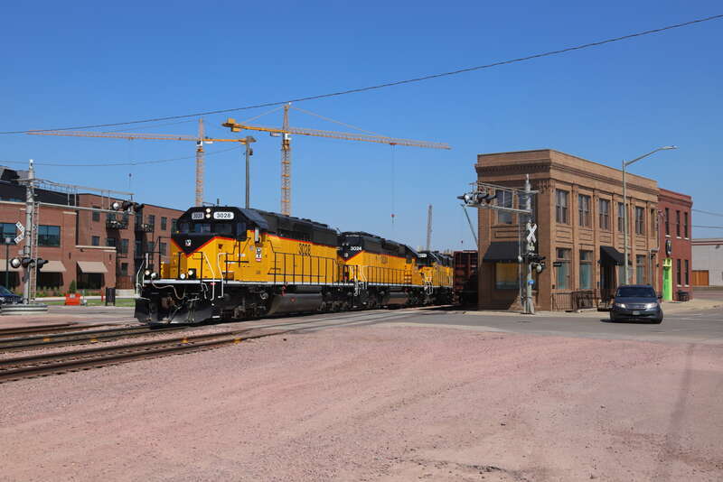 After waiting for traffic to clear on the Canton Sub, D&amp;I loads get underway in downtown Sioux Falls. Ahead is the grade south of town where the train stalled and had to shove back past here to 60th Street N to meet helpers coming down from Dell.
