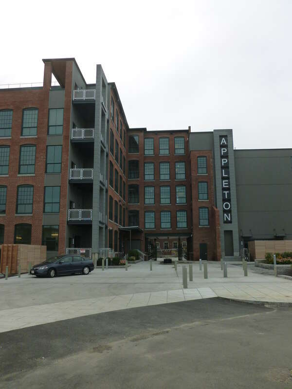 Appleton Mills, located at 219 Jackson Street, Lowell, Massachusetts.  North side of building shown.  The first floor of another mill in the Appleton Mills complex (240 Jackson Street) is visible through the main gate in this view.