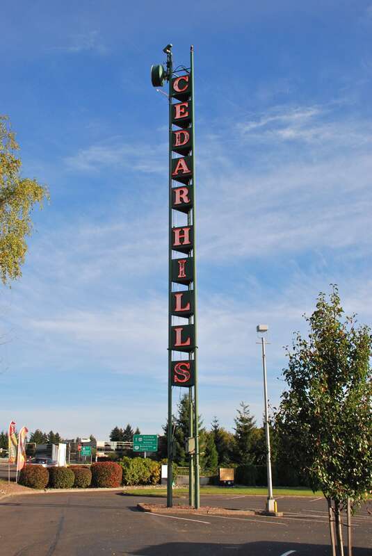 The tall, neon "Cedar Hills" sign, a local landmark – in place since the 1950s and visible from the nearby Sunset Highway (freeway). It is located in the parking lot of the Cedar Hills Shopping Center, which opened in 1955 and is located immediately