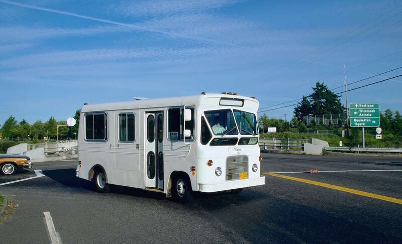 TriMet minibus No. 69, a "Flxette" model (manufactured by the Flxible Company), in service on a short-lived, unnumbered TriMet route between the Cedar Hills Transit Center and the Oregon Graduate Center, via Tanasbourne Mall. The minibus is turning