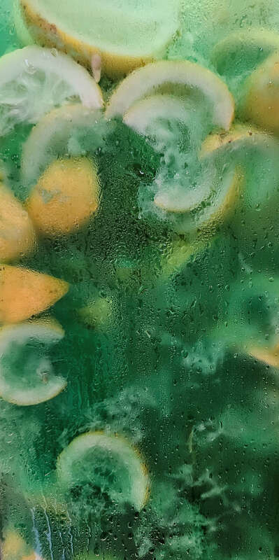 Container full of fresh limeade and lemons.