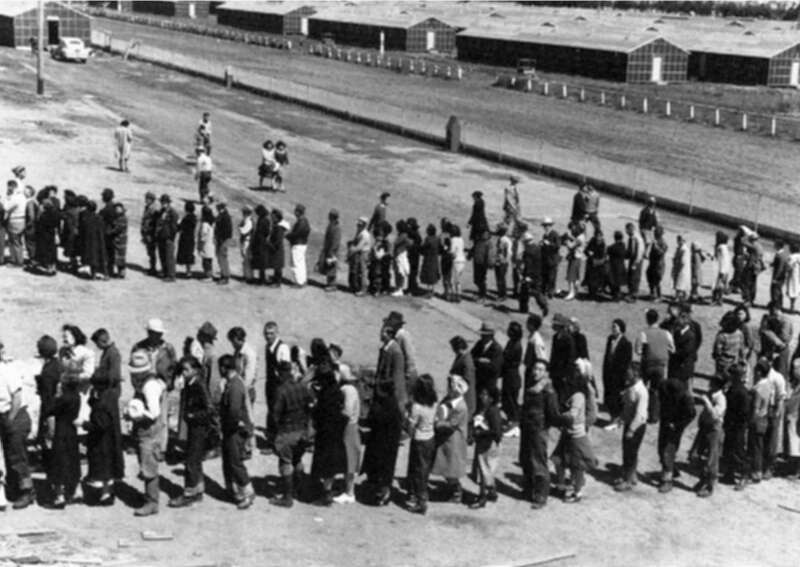 A Japanese-American internment center.  Description: This assembly center has been open for two days. Only one mess hall was operating today. Photograph shows line-up of newly arrived evacuees outside of this mess hall at noon. Tanforan Assembly