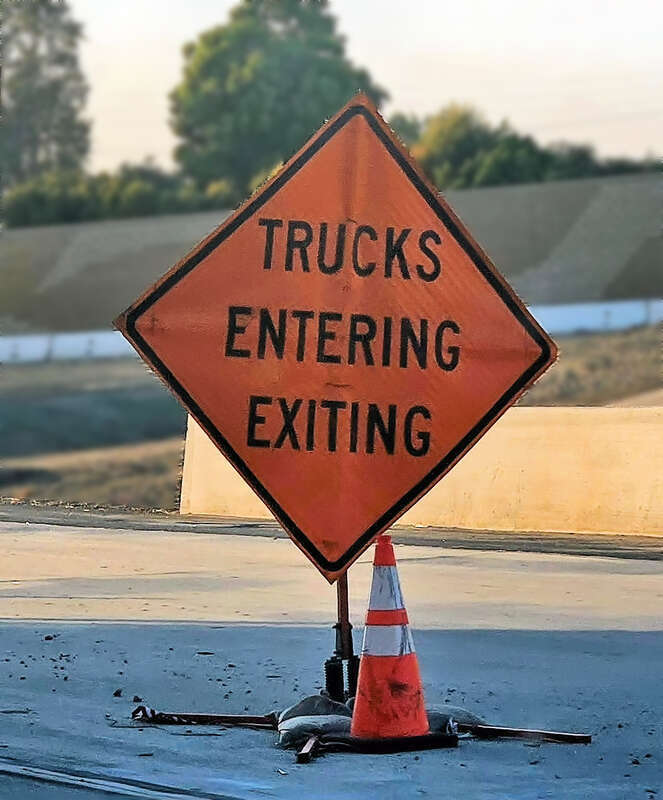 Trucks entering and exiting sign in a construction zone on Interstate 405, Westminster, California, USA.