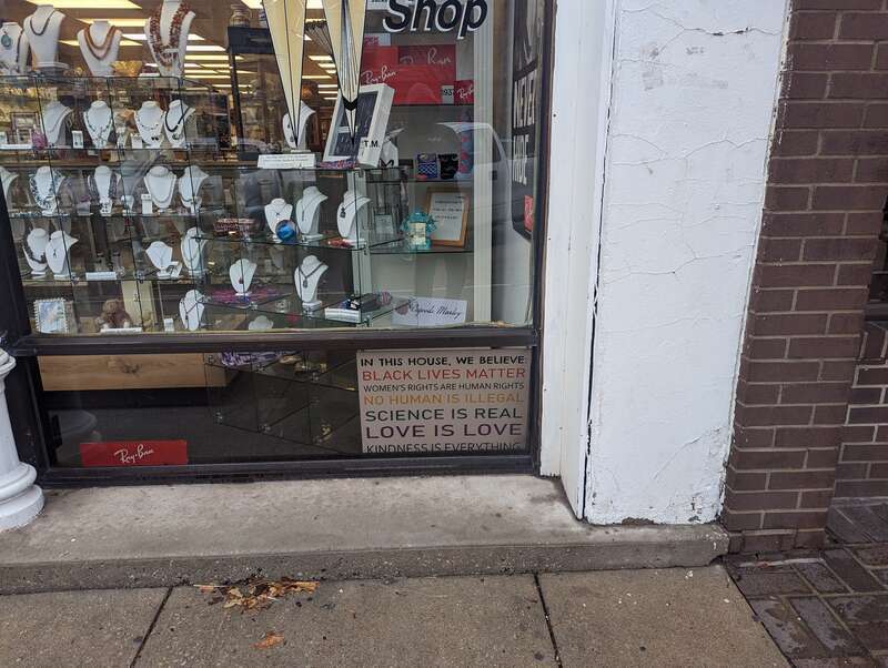 A "We Believe" sign (with a white background instead of the usual black) in a store window. Picture take in Lawrence, Kansas. Picture taken in March 2023.