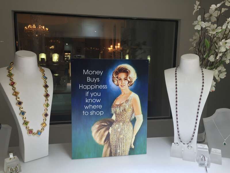 Jewelry store window display on Worth Avenue in Palm Beach, Florida, with a sign: "Money buys happiness if you know where to shop"