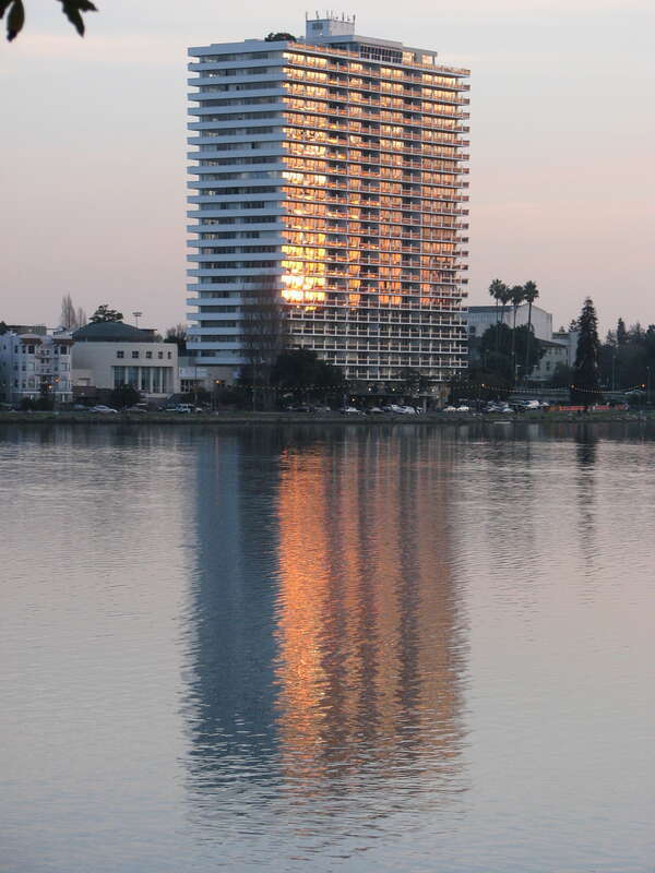 Lake Merritt high rise with its windows a blaze across the lake