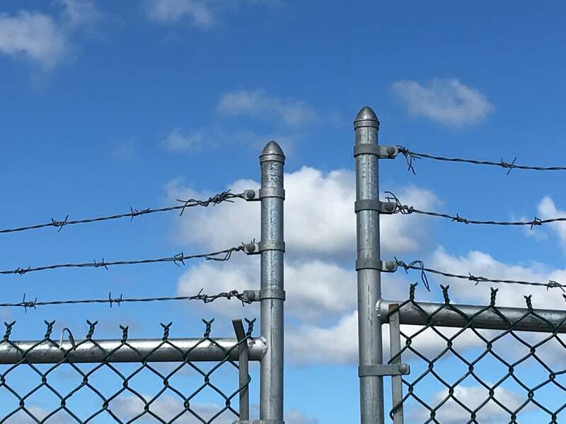 Barbed wire at the top of a fence's gate.