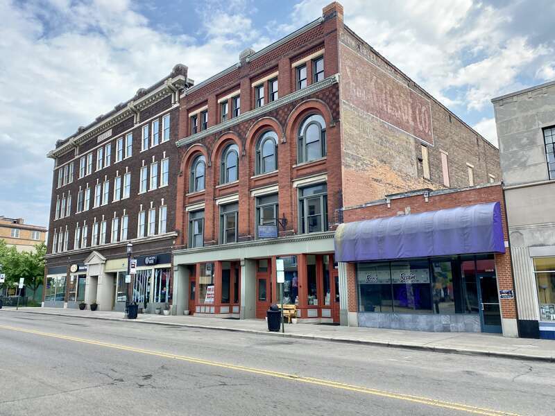 Built in 1895, this Romanesque Revival-style building features a red brick exterior, arched windows on the third floor, stone trim, decorative patterned brickwork, one-over-one double-hung windows, and a modified first floor retail shopfront.  The