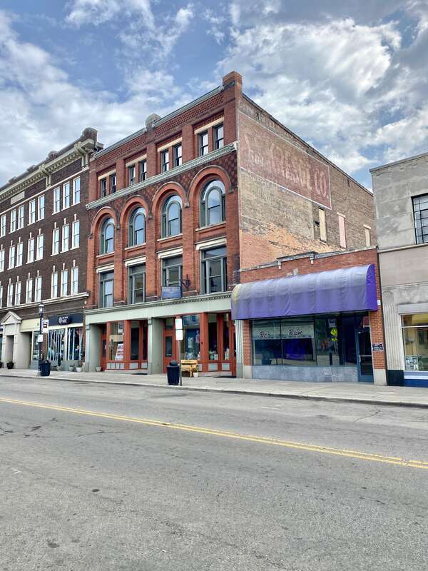 Built in 1895, this Romanesque Revival-style building features a red brick exterior, arched windows on the third floor, stone trim, decorative patterned brickwork, one-over-one double-hung windows, and a modified first floor retail shopfront.  The