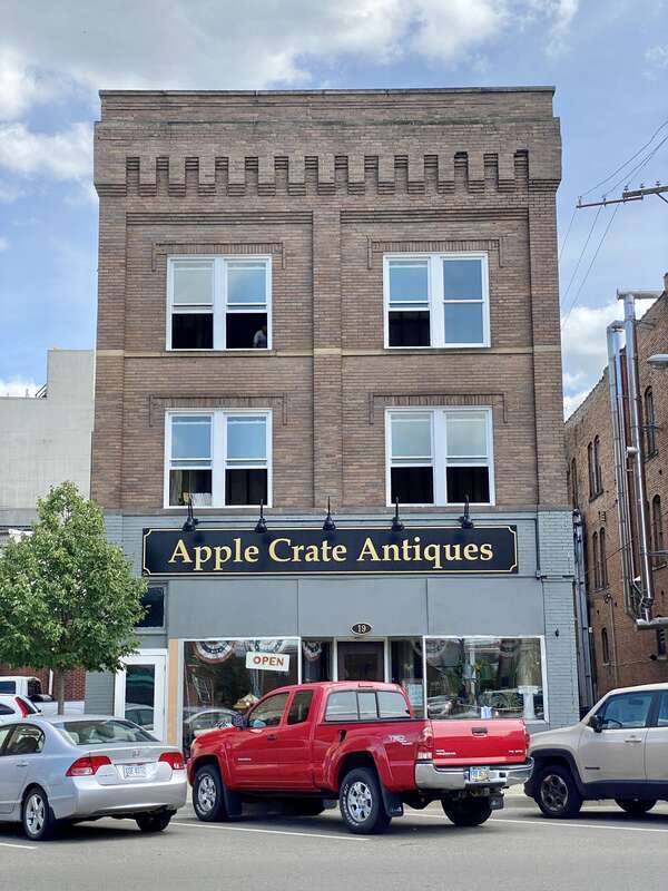 Built around the turn of the 20th Century, this building features a brown brick facade, paired one-over-one windows, stone belt coursing, brick cobbling, a rooftop parapet, a modified first floor retail shopfront, a low-slope shed roof, and an entry