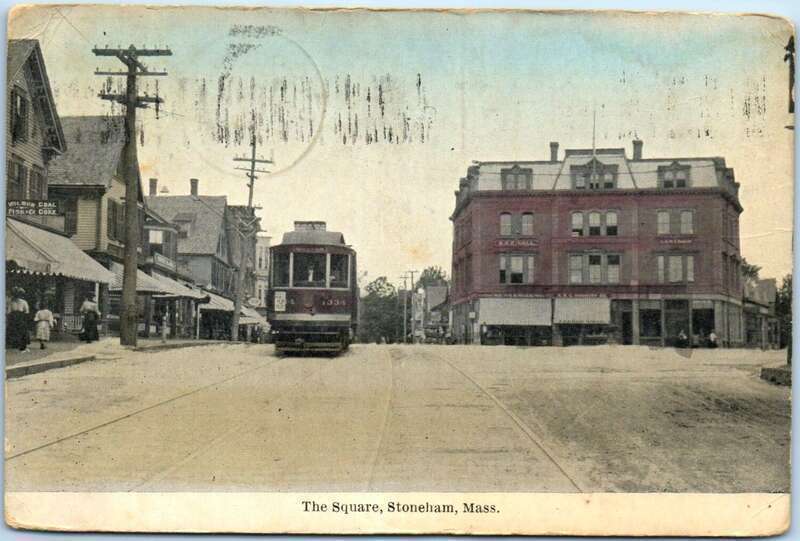 Divided back postcard of the Dow Block at Stoneham Square, with a Boston-bound streetcar at left
