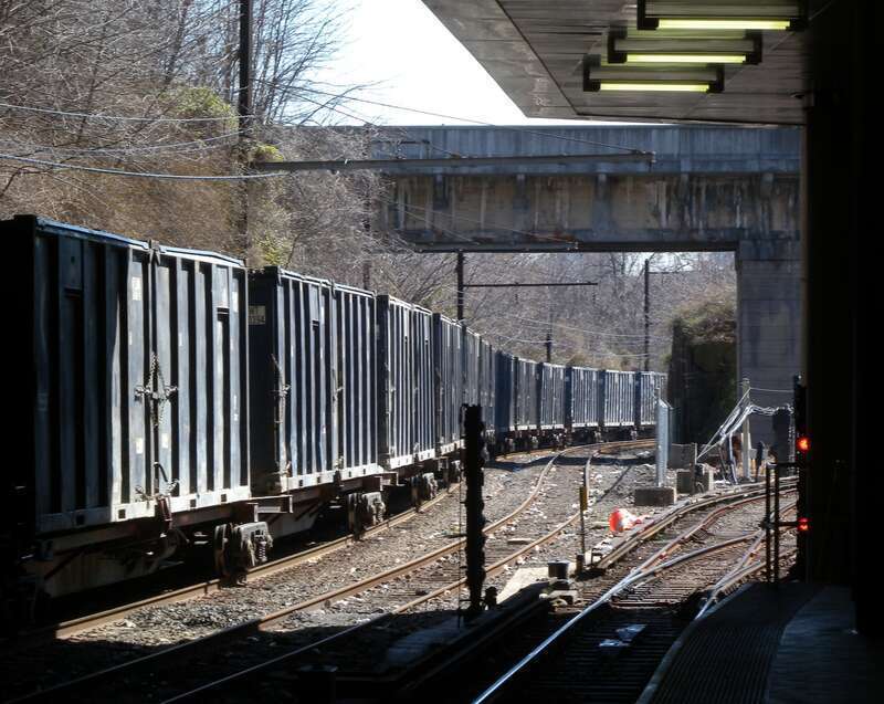 Looking east along the en:Bergen Hill Cut from westbound platform of JSQ station, as freight (garbage?) train passes under Summit Avenue and enters the station on a sunny midday.