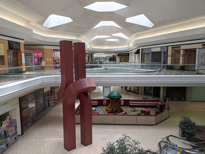 An abstract deep red sculpture at Lakeforest Mall with a children's play area behind it.  Many of the stores in the mall are now vacant. 701 Russell Avenue, Gaithersburg, Maryland 20877.