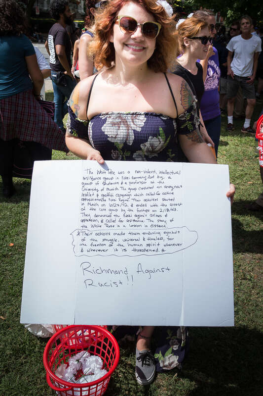 A member of a peaceful anti-fascist group handing out flowers at the Robert E. Lee statue on Monument Avenue, in Richmond, Virginia on September 16, 2017 smiles just yards from pro-Confederacy demonstrators. Pro-Confederate supporters and