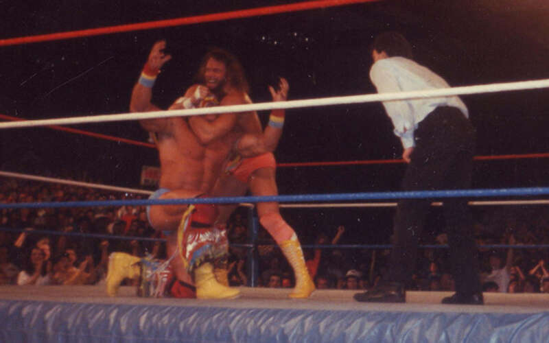 Randy Savage applying a headlock to The Ultimate Warrior