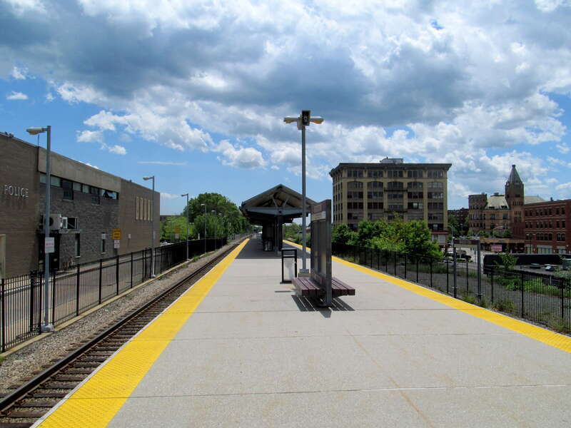 Brockton station platform in June 2017. The police station (built in 1967 on the foundation of the former railroad station) is a left; the Anglim Building is at right.