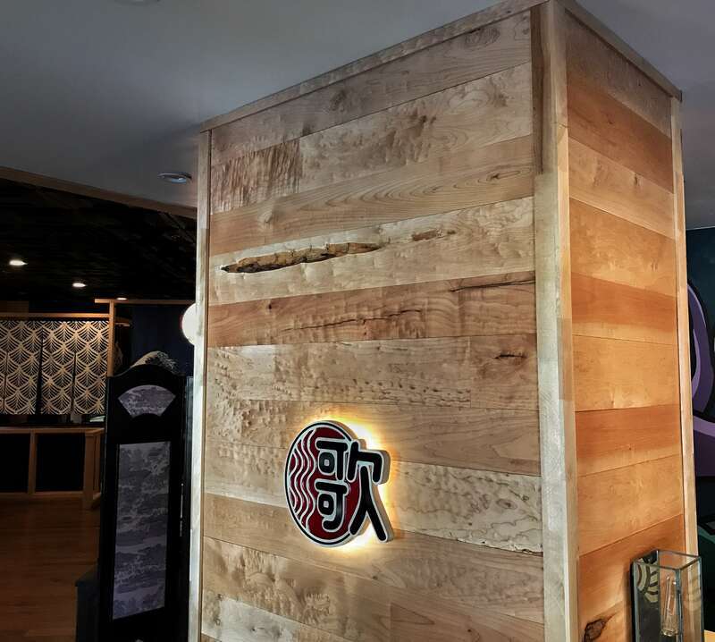 Wide planks of figured maple wainscot on a restaurant wall. The wall panels have a natural finish.