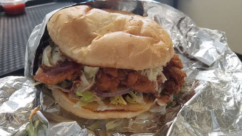 A fried chicken sandwich with Memphis BBQ sauce, Coleslaw, lettuce, and tomato from a restaurant in Winston-Salem, North Carolina