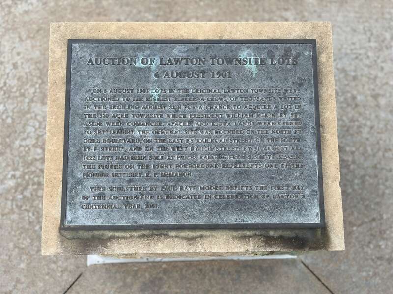 The commemorative relief plaque is entitled Auction of Lawton Townsite Lots 6 August 1901 located at the front of the relief sculpture.