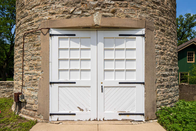 Door, Water tower, Ellwood House, DeKalb, Illinois. "On the west (rear) of the Ellwood House, the circular limestone water tower is about 50 feet (15.2 m) tall and has a diameter of 18 feet (5.5 m). The tower has windows occurring at different