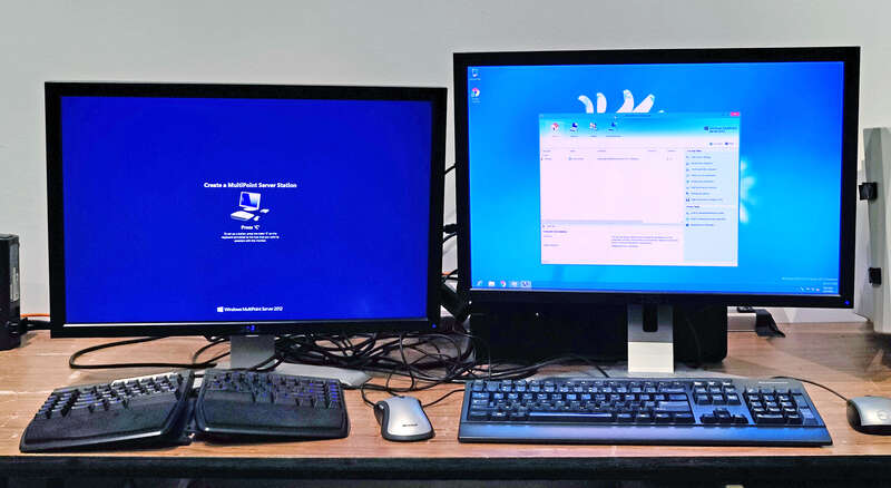 Microsoft Windows Multipoint Server 2012 displaying one active desktop session, and a station setup prompt on a separate display, prompting the user to press a button to identify the keyboard (and attached USB hub) to associate with a new session on