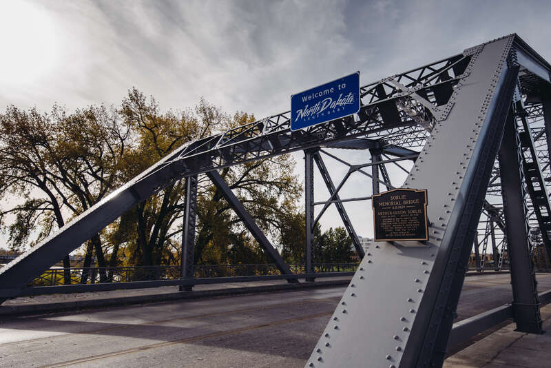 A North Dakota welcome sign on the Sorlie Memorial Bridge over the Red River, connecting East Grand Forks, Minnesota to Grand Forks, North Dakota.