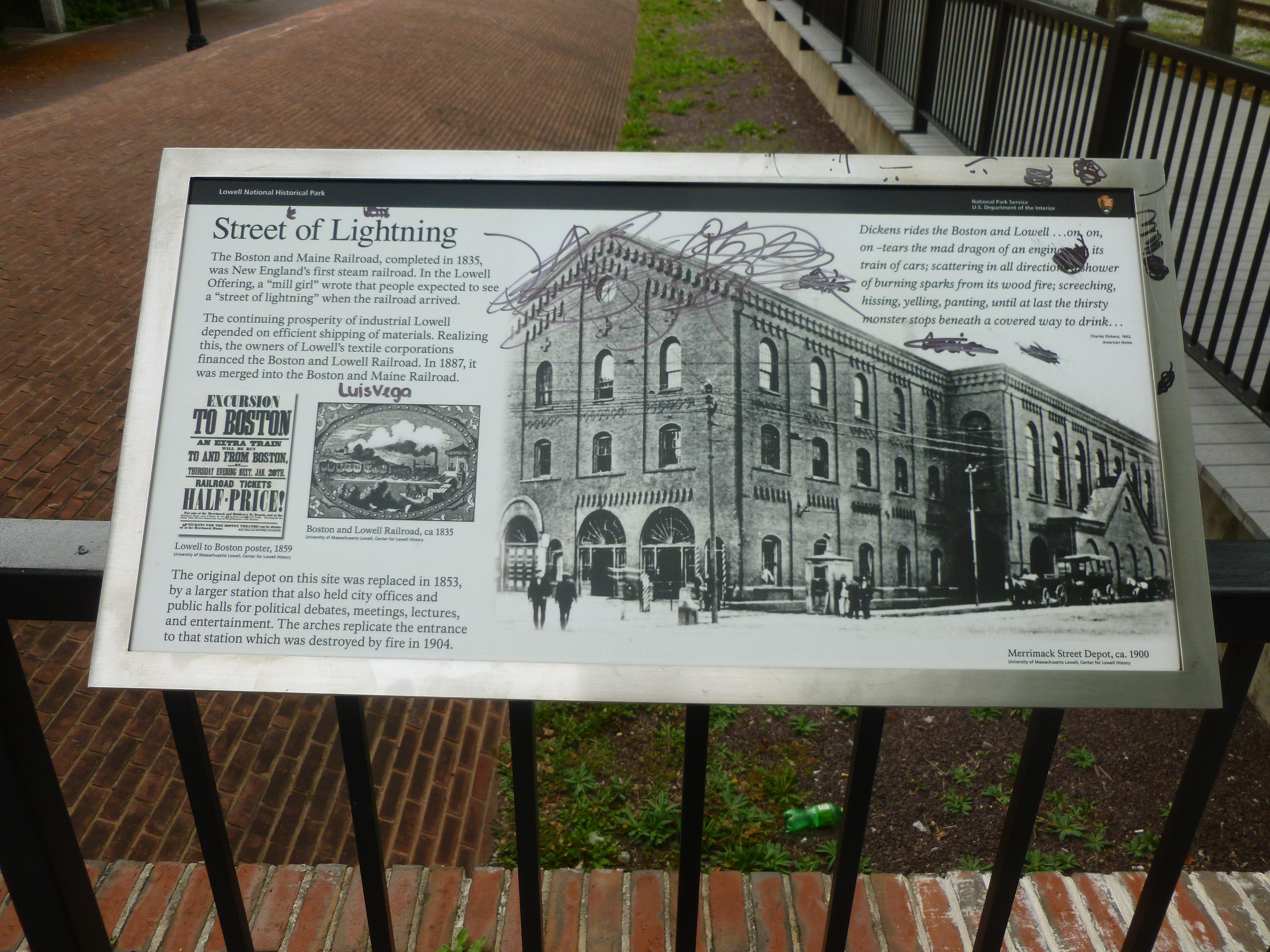 'Street of Lightning', a panel describing early railroad operations of the Boston and Lowell Railroad and the Boston and Maine Railroad in Lowell in the 1800's.  The panel is scribbled with vandalism.
