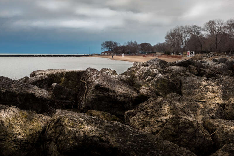 Large limestone blocks form a breakwater for Greenwood Street Beach in Evanston, Illinois.   Early morning, about 10 minutes past  sunrise, looking south.