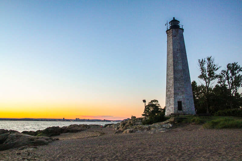Five Mile Point Lighthouse at sunset with the New Haven skyline in the background