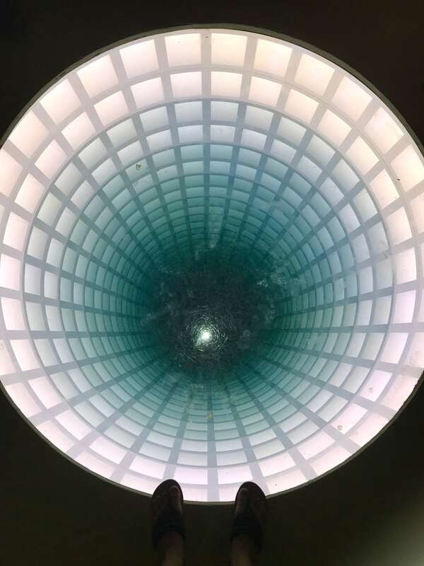 A sculpture made from glass and wood that creates the illusion of a tunnel descending deep into the Earth