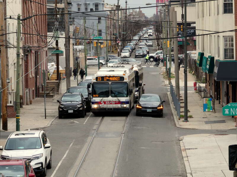 A pair of southbound SEPTA route 23 buses near Buttonwood Street in March 2022. The former southbound streetcar track is visible.