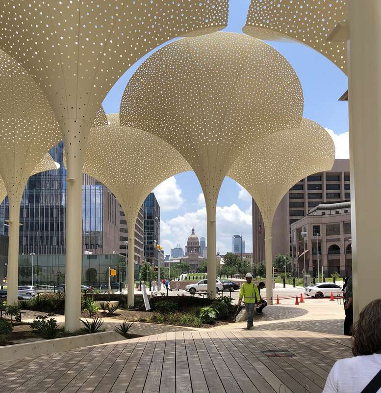 Exterior grounds and plaza designed by Snøhetta at the Blanton Museum of Art in Austin, Texas. Features include twelve towering, three-stories-tall "petals" which provide perforated shade. In the distance is the Texas State Capitol building. Photo by