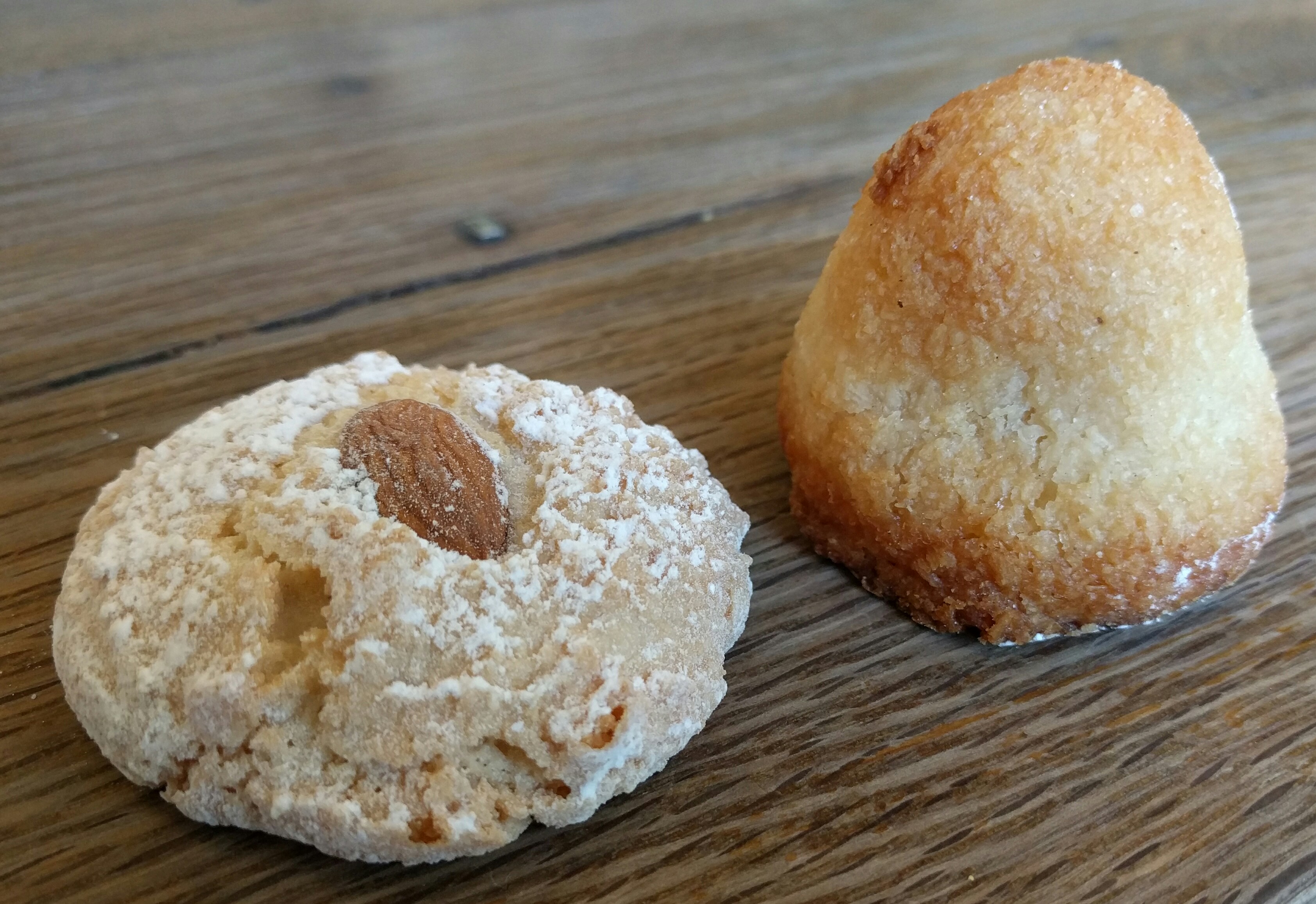 One almond macaroon and one coconut macaroon on a wooden tabletop at Hi-Rise Bread Company, Cambridge, Massachusetts