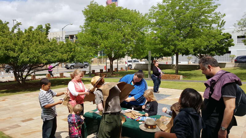 a family of adults and children stand around a table with a park ranger coloring on paper vests.
Making Junior Ranger vests together.
Keywords: junior ranger