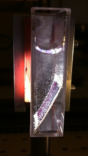 A sample of a photo electric cell in a lab environment.  Catalysts are added to the cell, which is submerged in water and illuminated by simulated sunlight.  The bubbles seen are oxygen (forming on the front of the cell) and hydrogen (forming on the